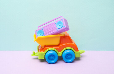 Toy dump truck with boombox audio tape recorder on a pastel background