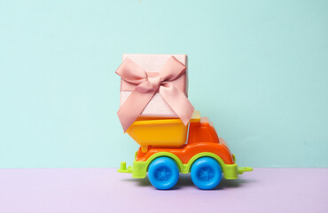Toy dump truck with gift box on a pastel background