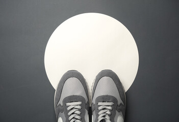 Gray sneakers on a white circles. Gray background. Creative idea. Fashion concept. Top view