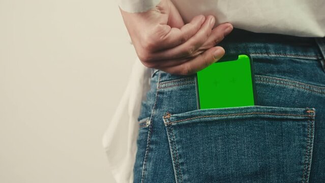 Smartphone phone with a green screen chroma key in the back pocket of jeans pants. Phone with chroma key close-up.