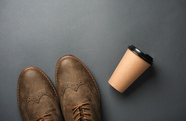 Men's brogue shoes with cup of coffee on dark gray background - obrazy, fototapety, plakaty