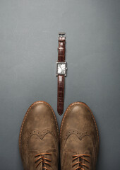Men's brogue shoes with wristwatch on dark gray background. Male style. Top view