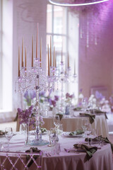 A table setting in a restaurant with a white tablecloth, a green napkin, a small vase with purple flowers, and various glasses. Concept for illustrating fine dining or hospitality services.