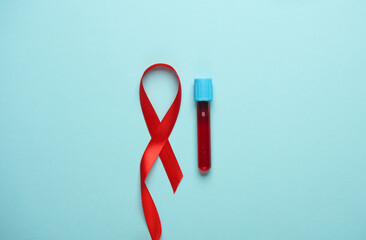 Red AIDS Awareness Ribbon and blood test tube on Blue Background