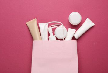 PAper bag with beauty products on pink background. Top view. Flat lay