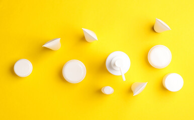 Set of beauty products bottles on yellow background. Top view. Flat lay