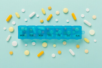Daily pill box with medications on color background, top view