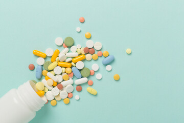 Jar with different medical pills and capsules on color background, top view