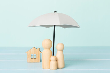 Wooden family figures under umbrella on wooden table
