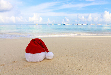 Fototapeta na wymiar Merry Christmas background with red hat on the white Caribbean sand.