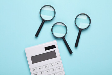 Magnifiers with calculator on blue background. Business concept