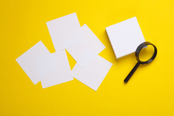White square memo papers with magnifying glass on yellow background