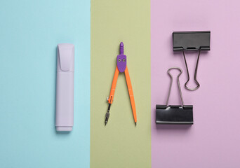 Marker, compasses and paper binders on a pastel background. School supplies. Top view