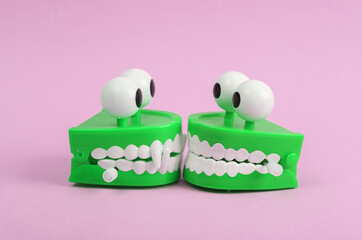 Funny toys clockwork jumping teeth with eyes on pink background