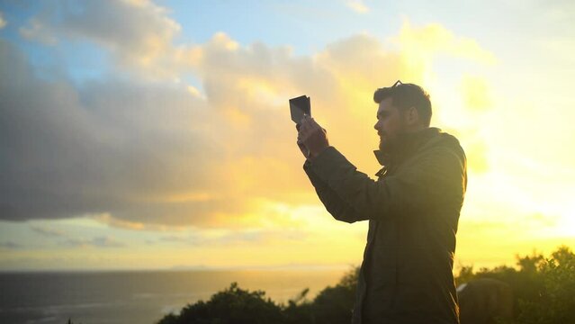 Nature, mountain and man with tablet for photography for landscape, natural environment and scenic view. Sunrise, morning and person on digital tech for picture, travel blog and memories by ocean