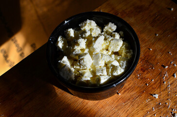 Homemade feta cheese on wooden cutting board.
