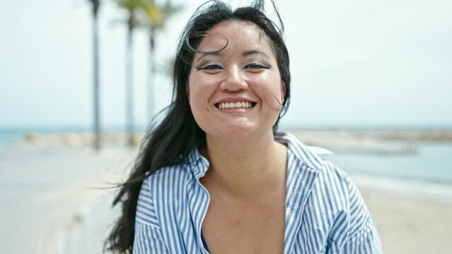 Young chinese woman tourist blowing kiss smiling at seaside