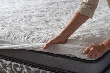 Woman putting protective mattress pad on a new mattress