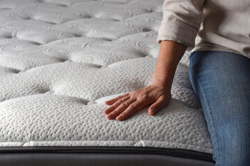 Woman sitting on a brand new mattress and touching the fabric