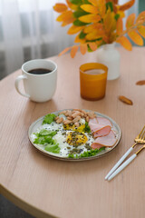 Autumn Home breakfast, vaze with yellow leaves,candle, grey plate with fried egg, sausage, bean and cup of coffee.