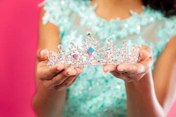 Cute hispanic girl holding a crown or tiara in her hand