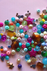 Various colorful beads on bright pink background. Top view.