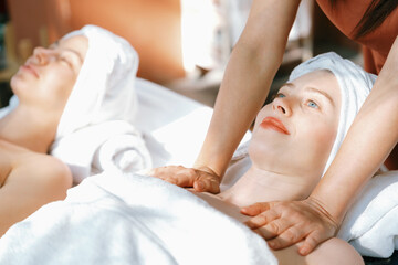 Obraz na płótnie Canvas A portrait of two beautiful woman having back massage by professional masseur and falling in deep relaxation surrounded by traditional spa environment. Calming and relaxing concept. Tranquility.