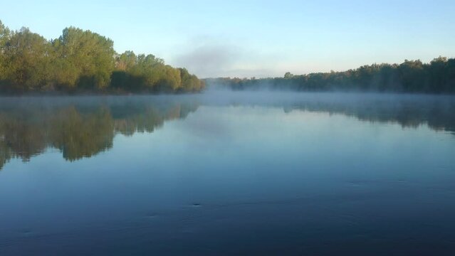 Potamology. Great Don River in middle reaches. River in morning appearance of sun above horizon. Trees tops of flooded forest are painted with first rays, fog creeps over water. Spring and high water