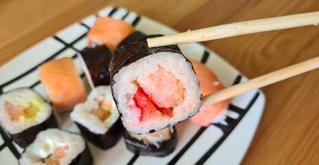 Hand with disposable chopsticks holds sake nigiri sushi with salmon