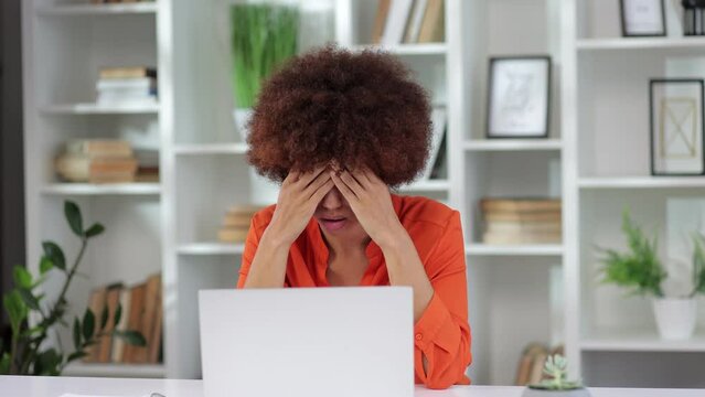 Tired african american woman worries overwork problems stress rubs head feels pain headache suffers difficult decision working with laptop file error bankruptcy debt