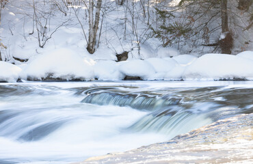 Rapids flowing in frozen river during hike