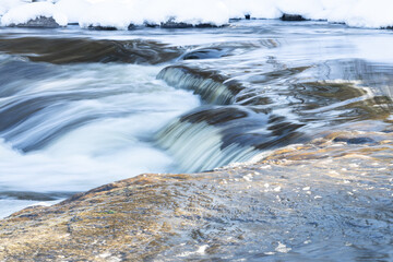 Rapids flowing in frozen river during hike