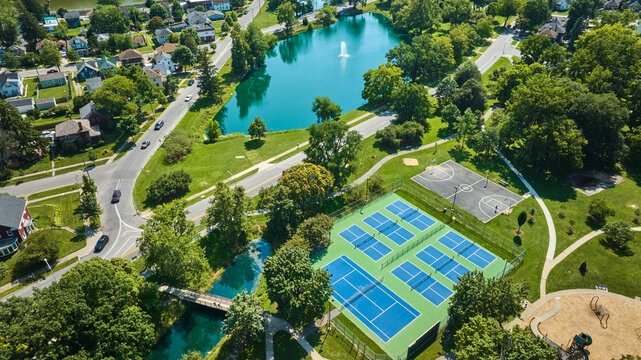 Lakeside Park Bridge Near Tennis Courts And Basketball Court With Neighborhood And Pond Aerial