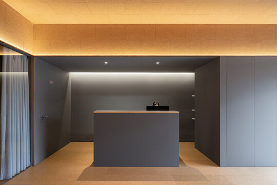 Anonymous person working at modern clinic reception with cork ceiling