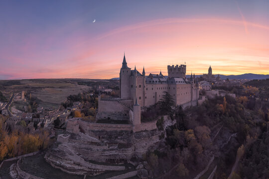 Drone view of medieval castle against sunset sky and moon