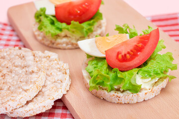 Rice Cake Sandwiches with Tomato, Lettuce and Egg on Wooden Cutting Board. Easy Breakfast. Diet Food. Quick and Healthy Sandwiches. Crispbread with Tasty Filling. Healthy Dietary Snack
