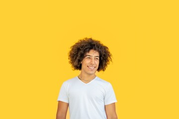 Portrait of smiling beautiful young mixed race Afro-Italian generation z teenager with thick curly hair on yellow background. Happy multiethnic young men. Positive emotions gen z guy, feelings.