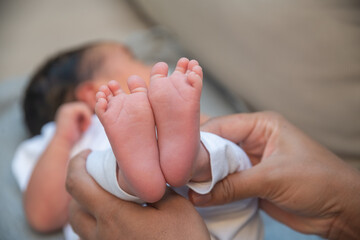 Crop faceless mother touching feet of cute infant