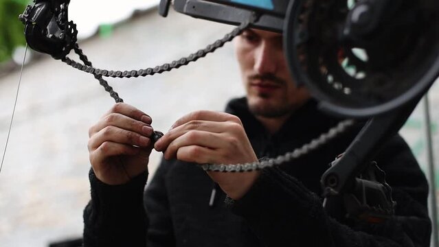 A young man connects a bicycle chain.