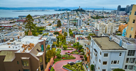 Aerial winding Lombard Street with cars going downhill with distant Coit Tower