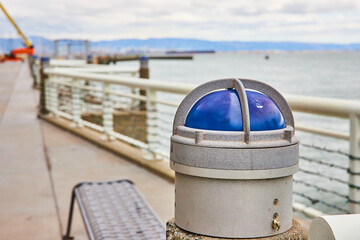 Blue light on heavy duty harbor railing with blurry background of San Francisco Bay