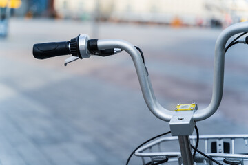 Bicycle steering wheel with black handles on a paving slab avenue