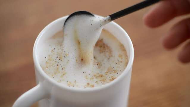 very appetizing coffee crema with a spoon stirring it in a white cup, latte coffee with milk and creamer