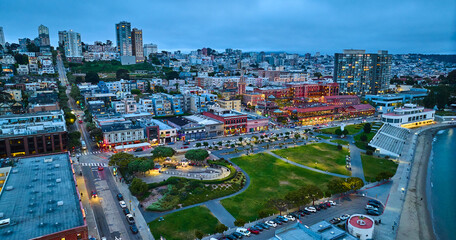 Aerial green park beside bay with Ghirardelli Chocolate Experience and other city buildings at dusk