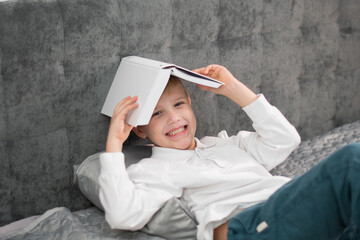 Toddler is messing around with a book. Little boy hiding under a book