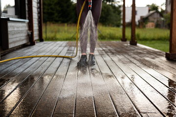 Woman washes a wooden terrace before painting it in her modern private house