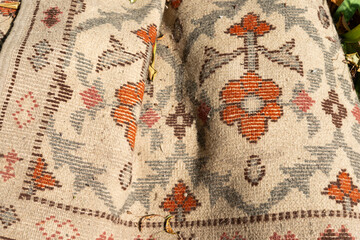 discarded woolen carpet with floral patterns (verso side) outdoors waiting to be recycled