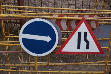 Road signs indicating detour to the right and warning drivers of one-way traffic nearby. Road...