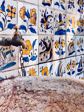 The beautiful stone sink, weathered by time, stands as a testament to history. Above it, intricate Portuguese Azulejo tiles tell a story of their own, adding a vibrant burst of colour. 