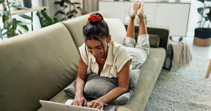 Laptop, email and relax with a woman on a sofa in the living room of her home for typing or browsing. Computer, smile and a happy young person lying on a couch in her apartment on the weekend